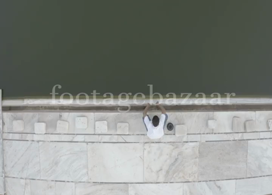 An aerial shot of a man washing his hands at a waterbody in Jama Masjid 