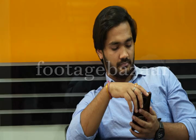 A Shot of an Indian Boy using phone in his office